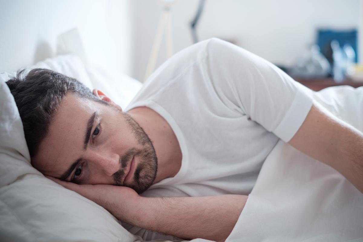 a man lays in bed as he experiences signs of meth addiction and wonders what does meth addiction look like