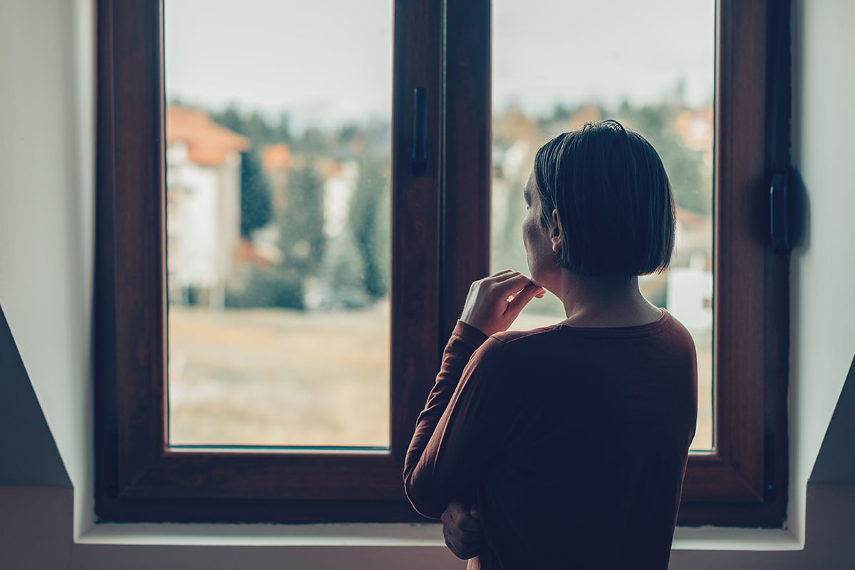 woman looking at window wondering how long heroin withdrawal will last